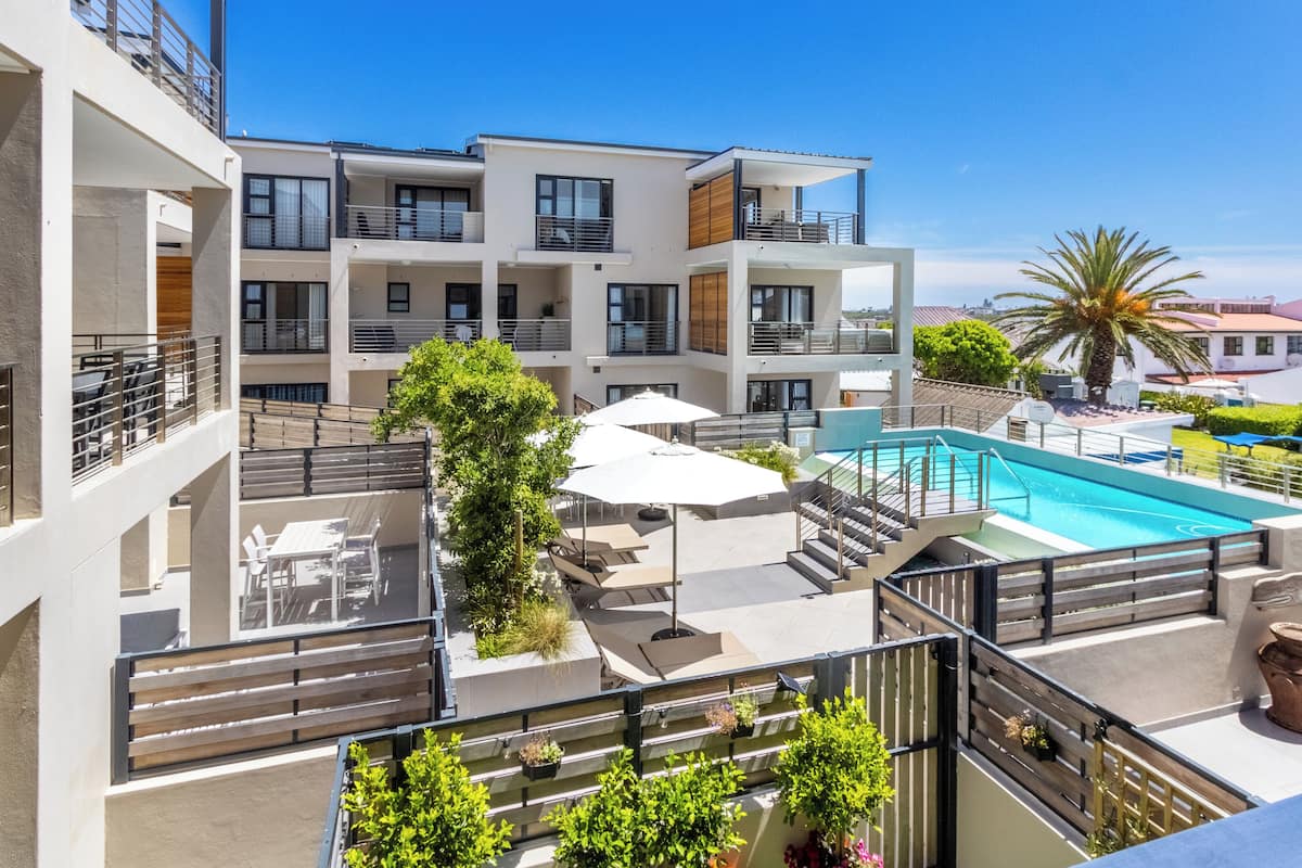 Un immeuble d’appartements moderne doté d’une piscine sur le toit, d’un espace extérieur aménagé et offrant une vue sur les environs.