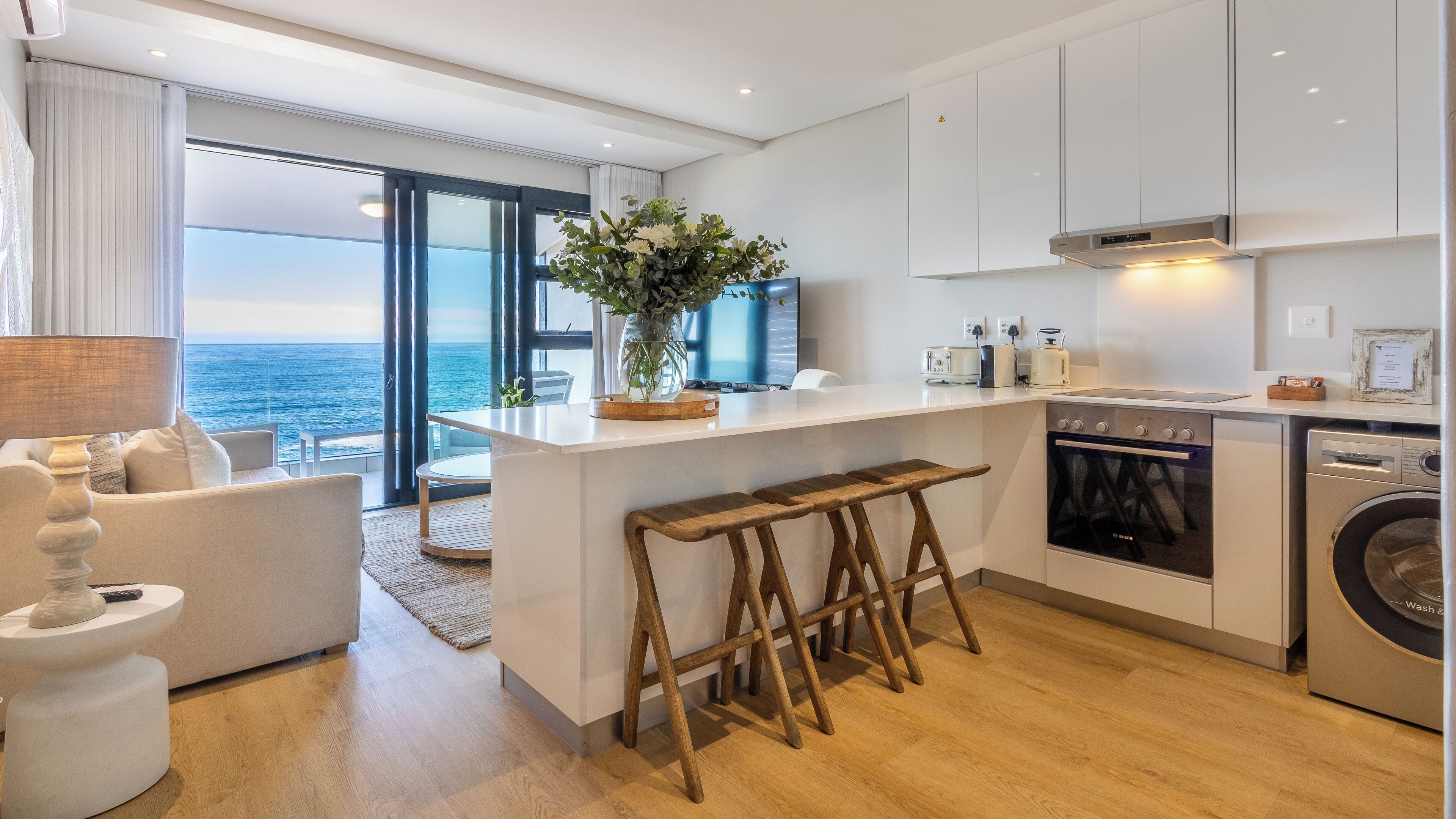 Una cocina moderna con vista al océano, un comedor con vistas y una zona de estar acogedora.