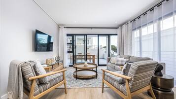 A modern living room with a large TV, wooden furniture, and a view of the outside.