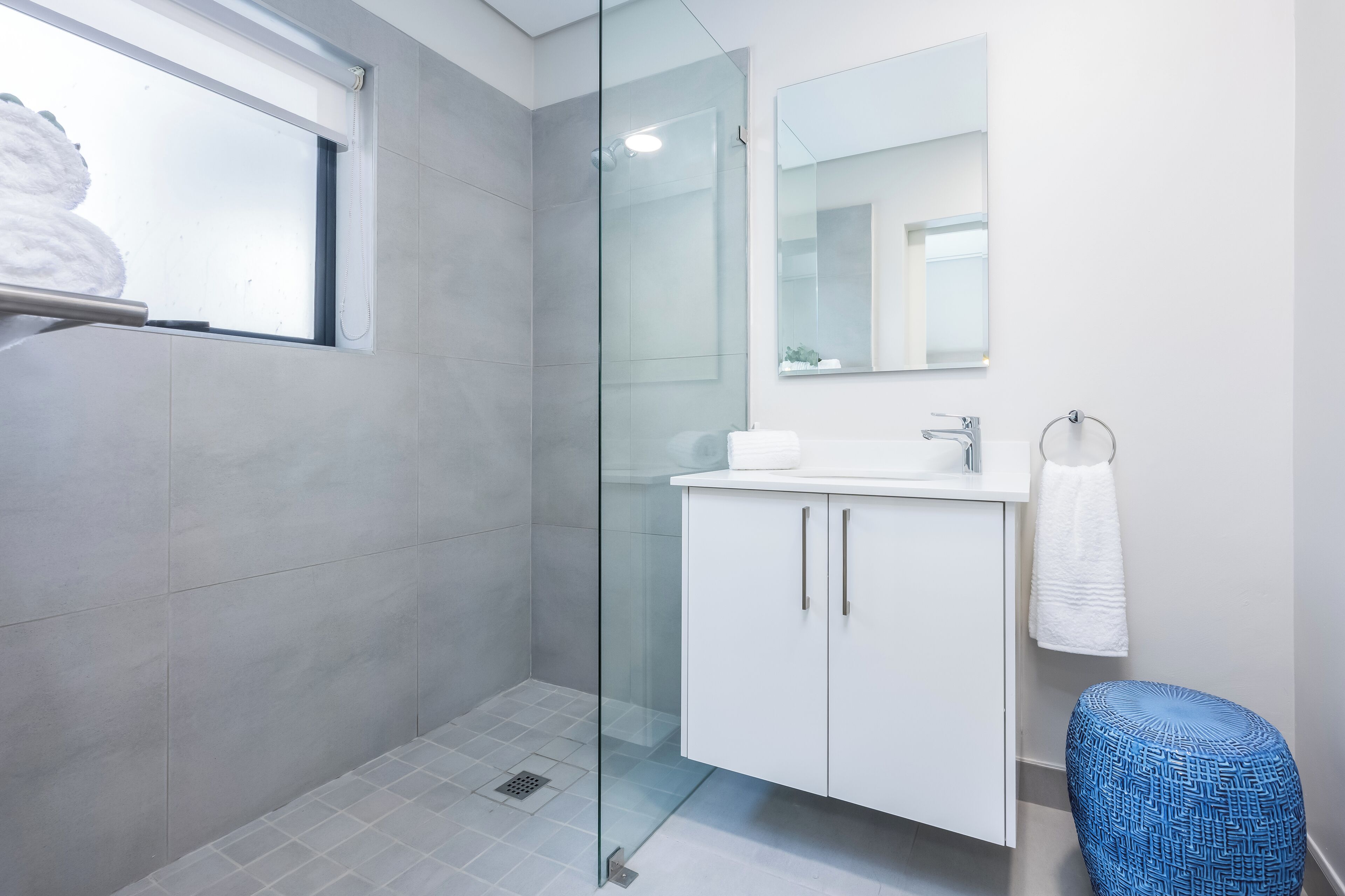 A modern bathroom with a glass shower enclosure, a white sink, and a large mirror.