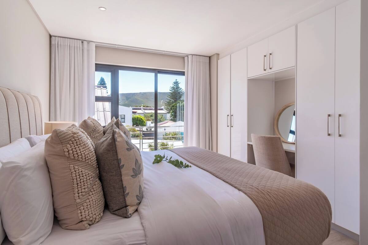 Une chambre à coucher moderne avec un grand lit, une table de chevet avec un miroir et une armoire.