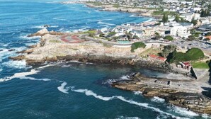 A coastal town with rocky cliffs, a beach, and buildings along the shore.