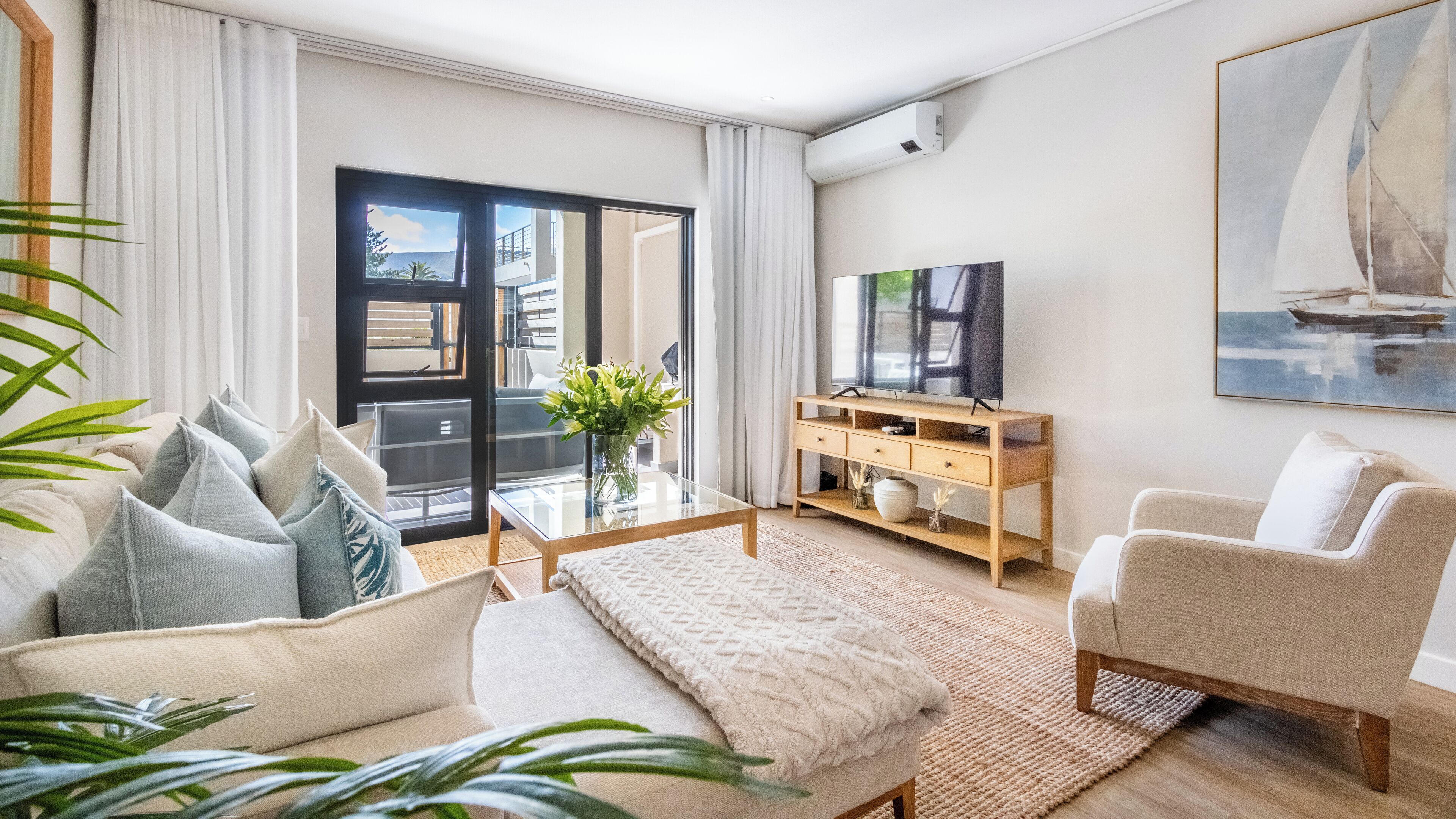 Una sala de estar moderna con un sofá, una mesa de centro, un televisor y un cuadro en la pared.