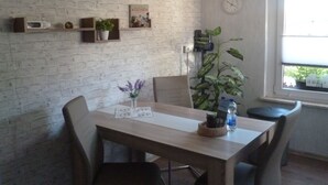 Un comedor con pared de ladrillo, un reloj, una ventana con vistas y una planta.