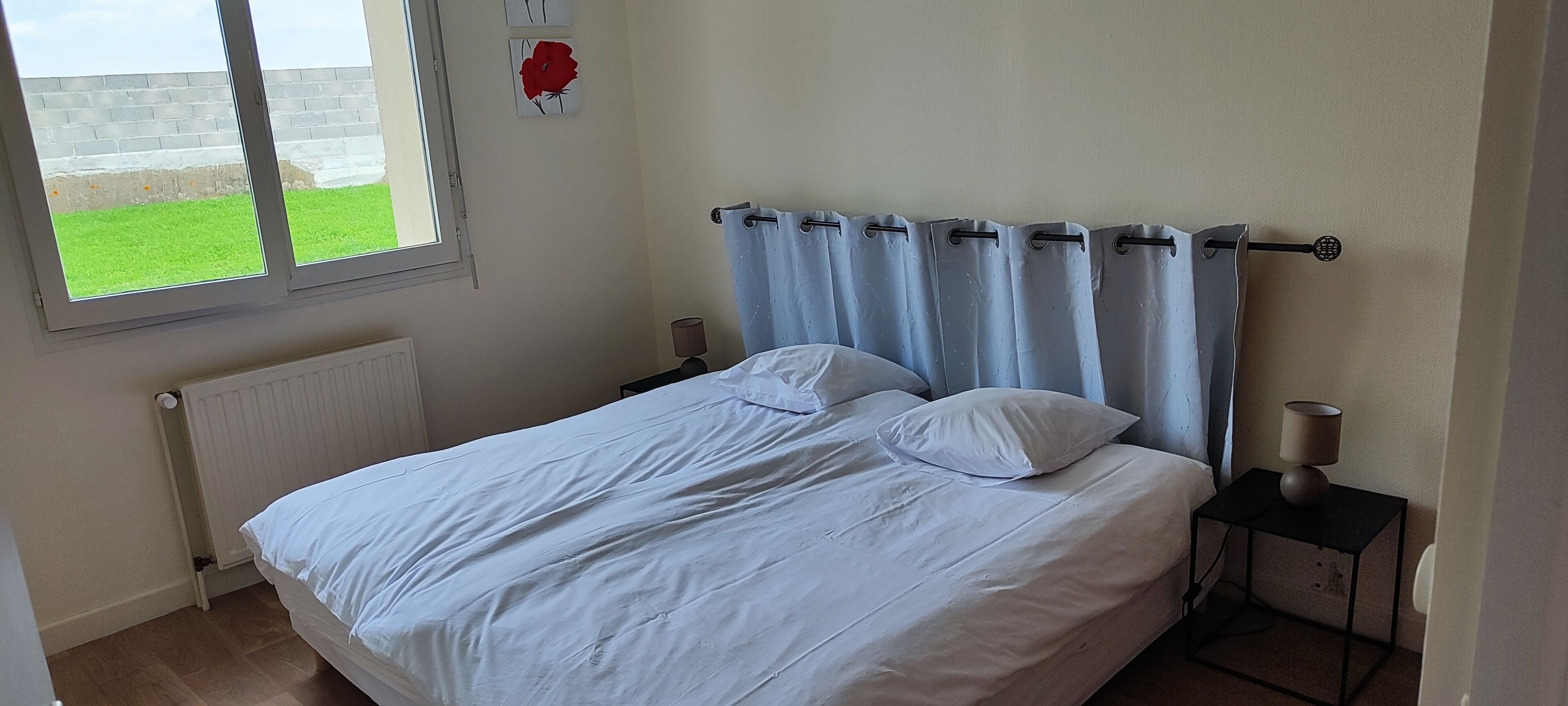 Een slaapkamer met een bed, twee nachtkastjes, een raam en een radiator.