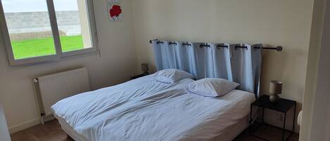 Een slaapkamer met een bed, twee nachtkastjes, een raam en een radiator.