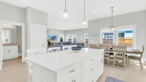 A modern kitchen with white cabinetry, a large island, and pendant lighting. - Tailwinds: Free golf cart, Private hot tub, Pool, Game room, 4min to beach (Miramar Beach)