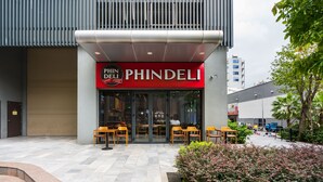 The exterior of a PHINDELI restaurant with outdoor seating and a modern facade.