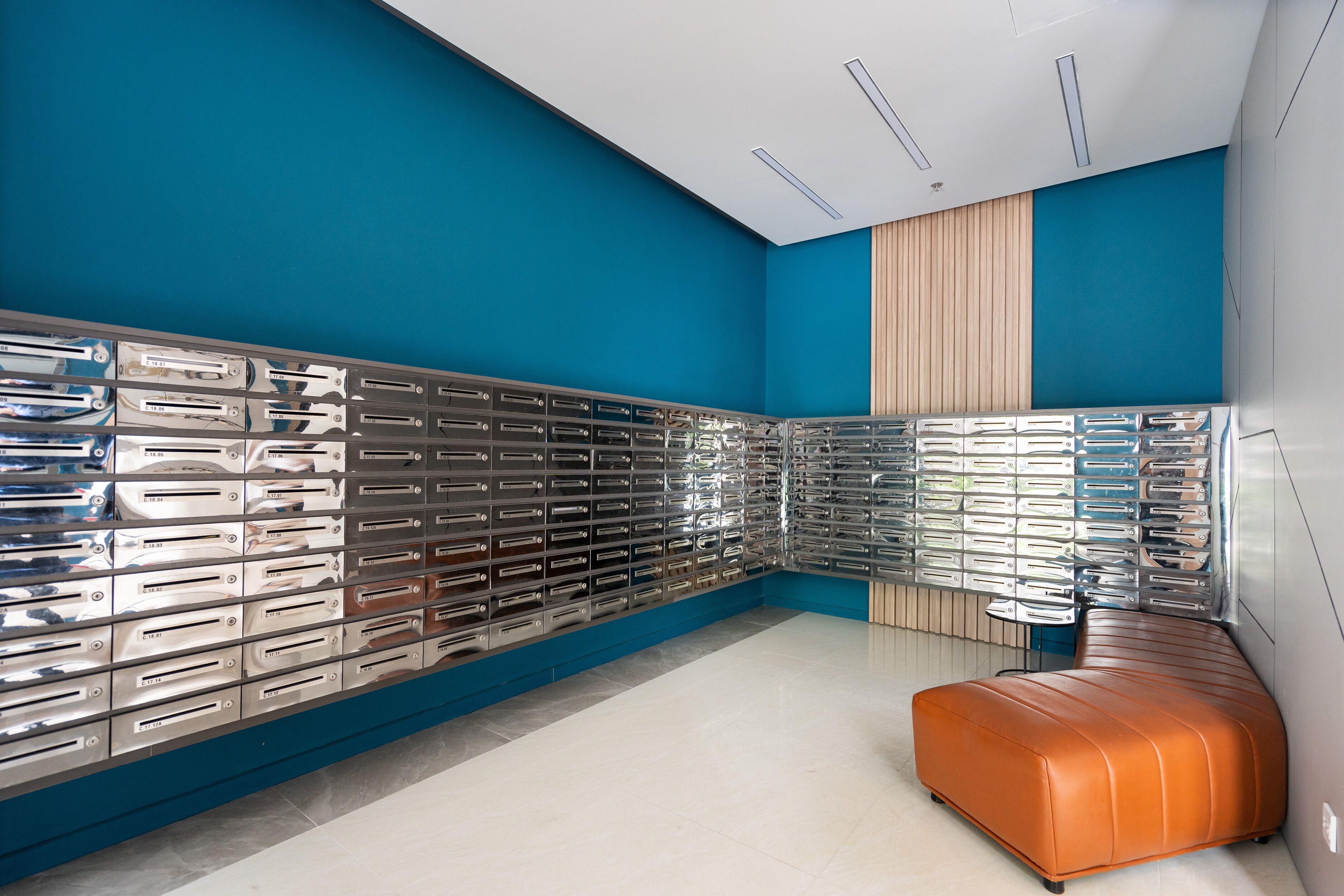 Una habitación moderna con una paleta de colores azul y blanco, un mueble de pared metálico y un reposapiés de cuero.