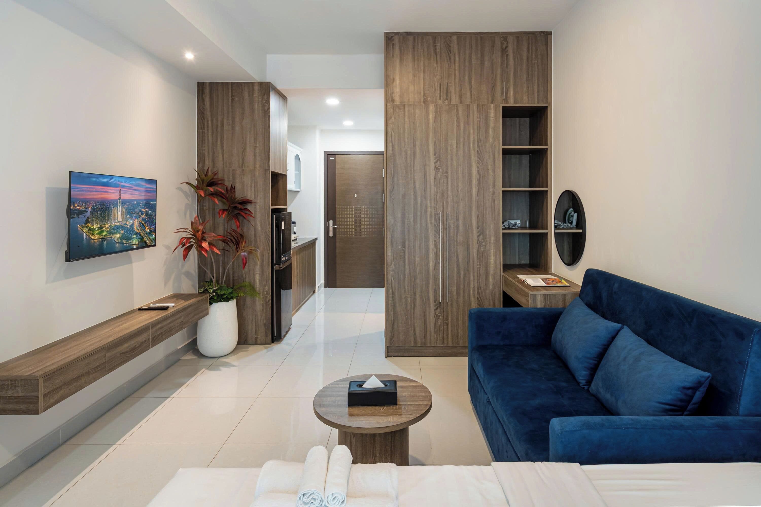 Una sala de estar moderna con un sofá azul, una mesa de centro, un televisor de pantalla plana montado en la pared y un mueble de madera.