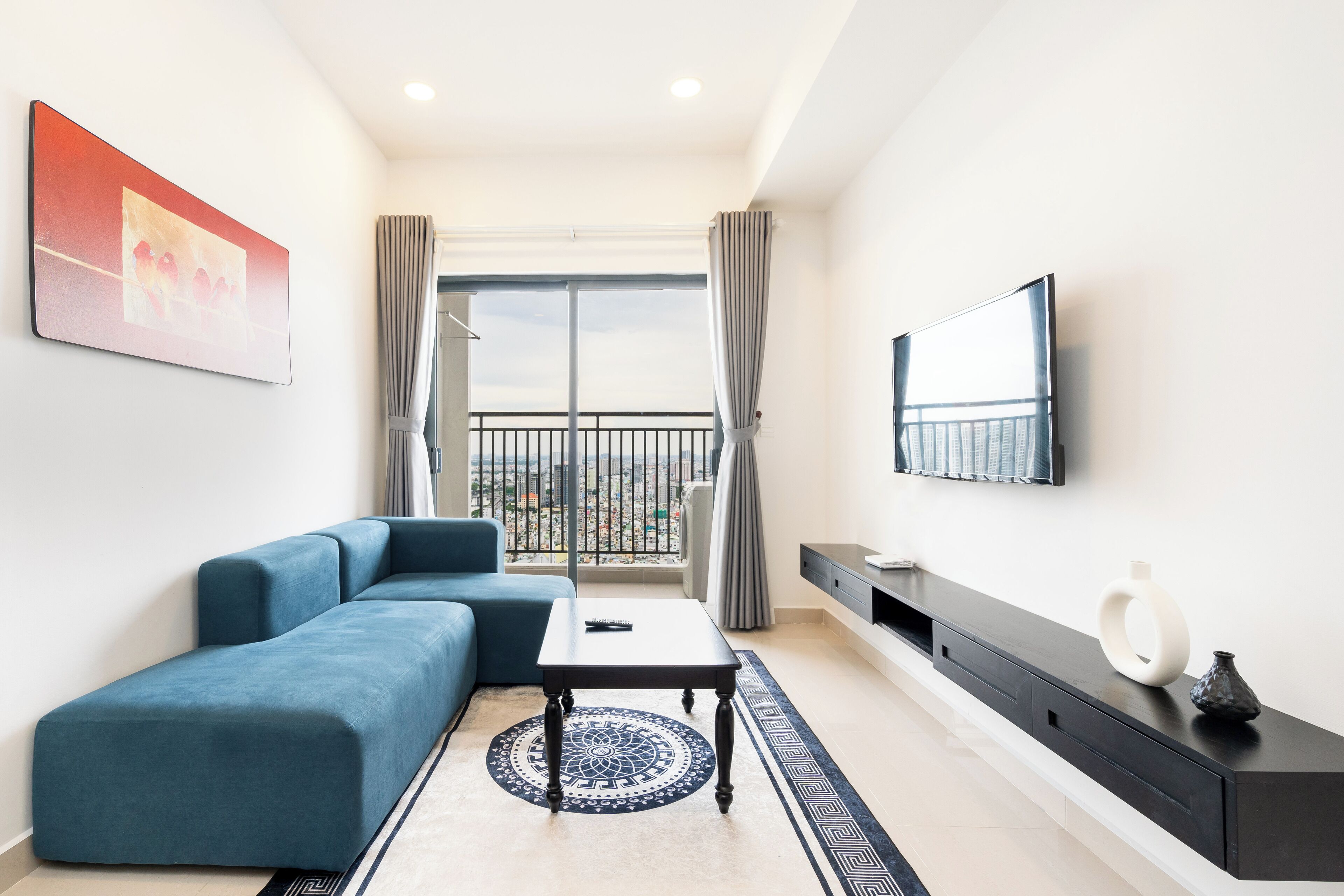 Een moderne woonkamer met een hoekbank, een salontafel, een aan de muur bevestigde televisie en een balkon met uitzicht.
