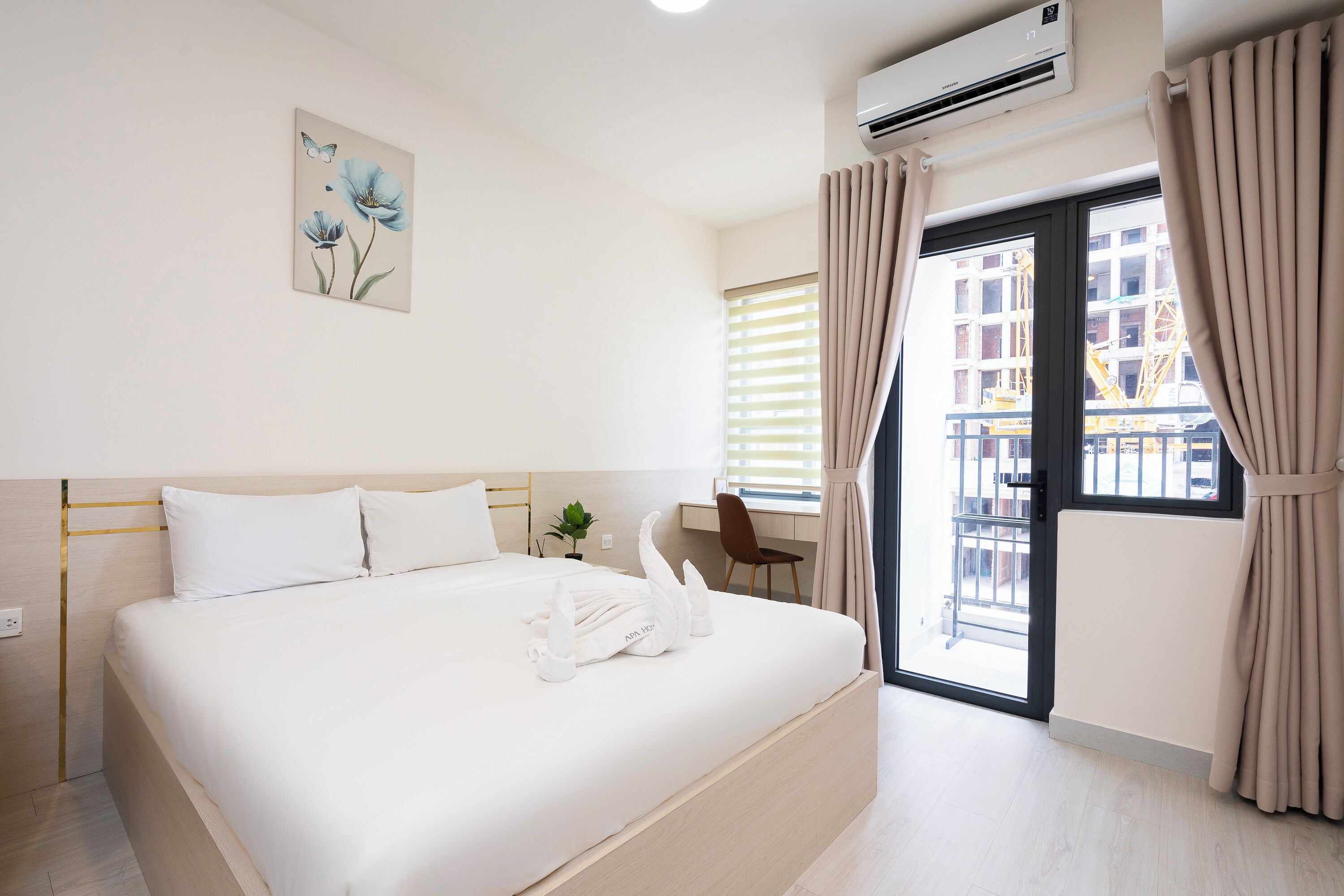 Ein Hotelzimmer mit Bett, Schreibtisch, Fenster mit Vorhängen und Klimaanlage.