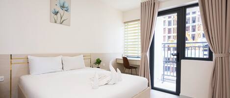Een hotelkamer met een bed, een bureau, een raam met gordijnen en een airconditioning.