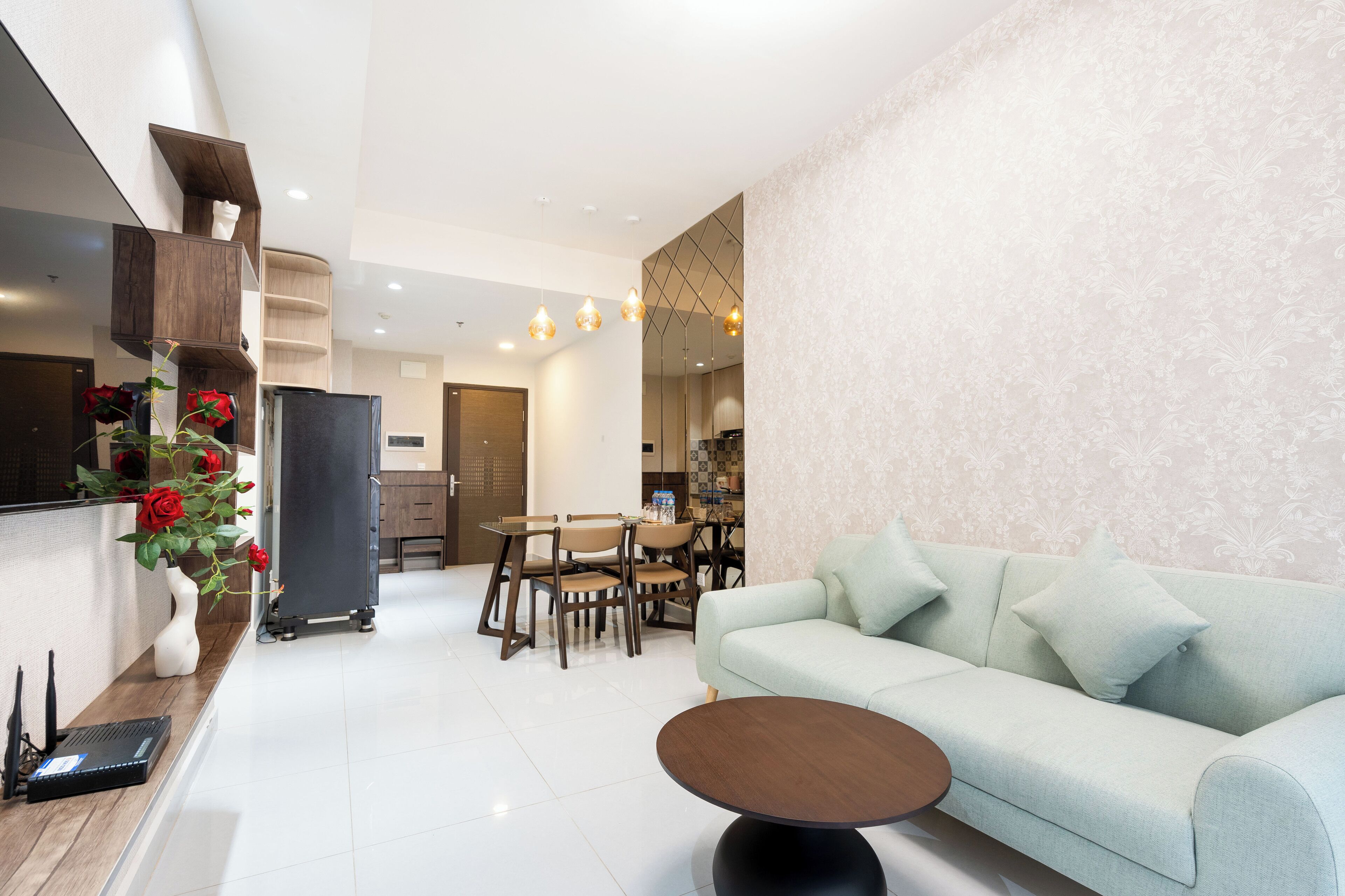 A modern living room with a sofa, a coffee table, and a dining area with chairs and a table.