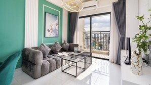 A modern living room with a grey sofa, a coffee table, and a large window with curtains.