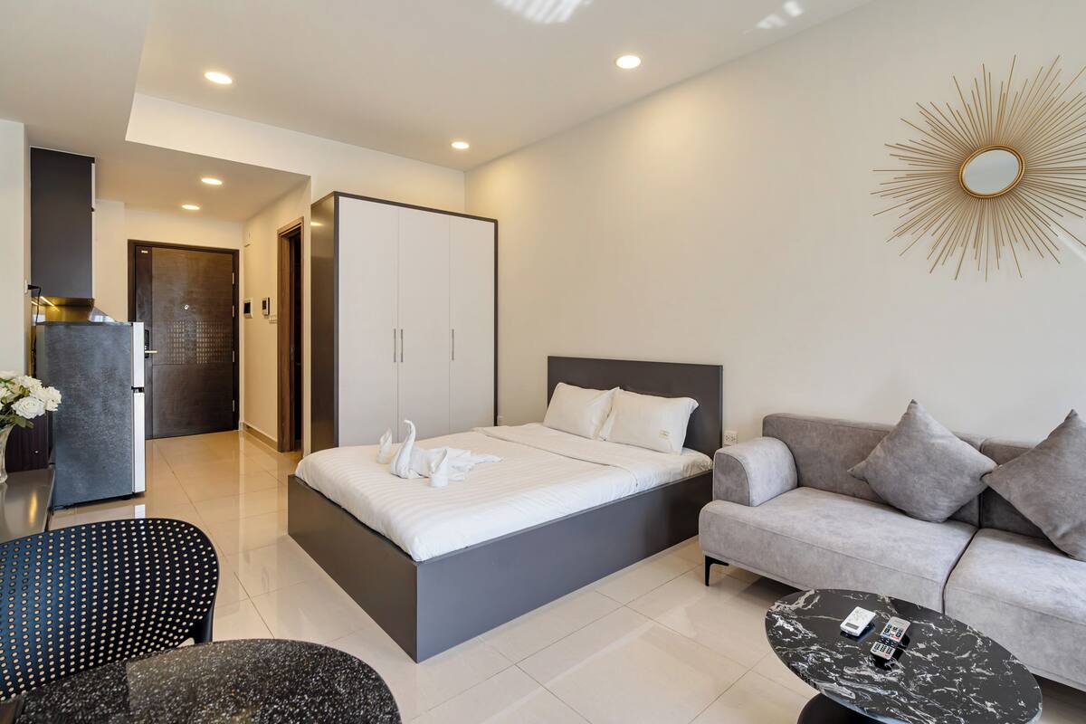 Una habitación de hotel moderna con cama, sofá, mesa de centro y un espejo decorativo.