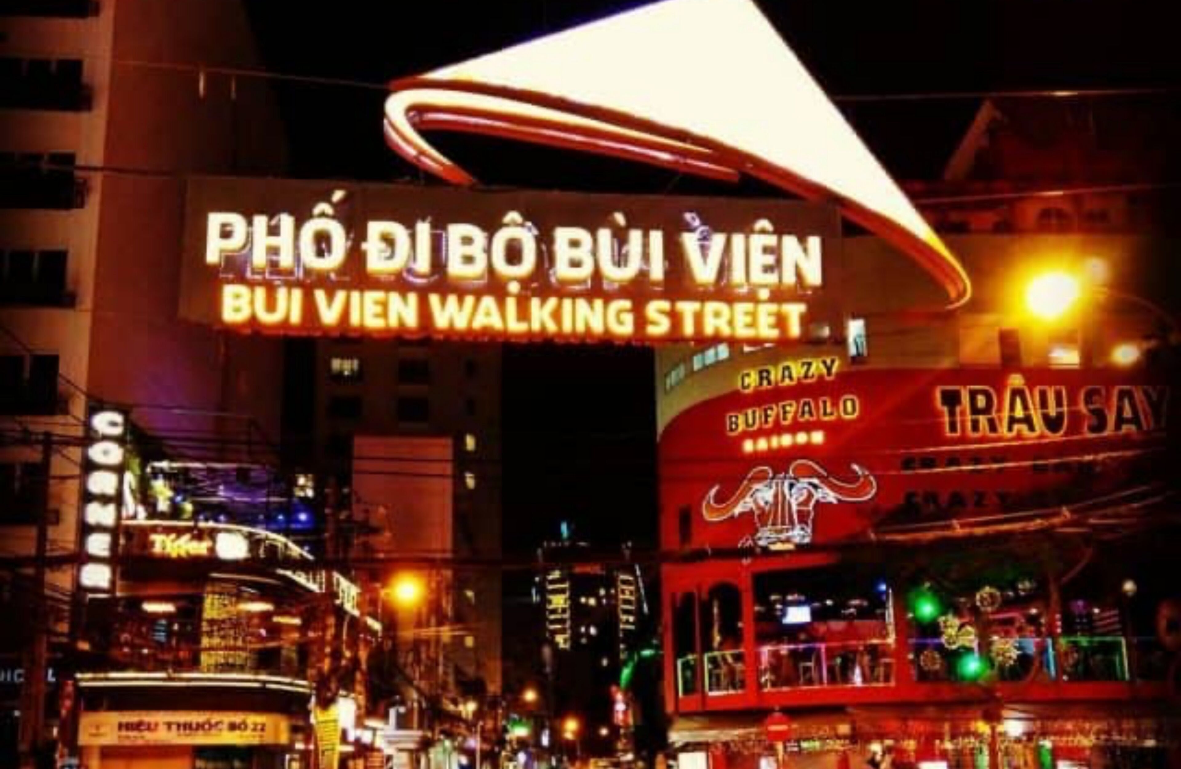 A brightly lit street with a neon sign for "BUI VIEN WALKING STREET" and a buffalo-themed bar named "BUFFALO CRAZY TRAUSAN".