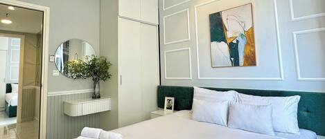 Ein Hotelzimmer mit einem großen Bett, einem Nachttisch, einem Spiegel, einem Wandbild und einer Deckenleuchte.