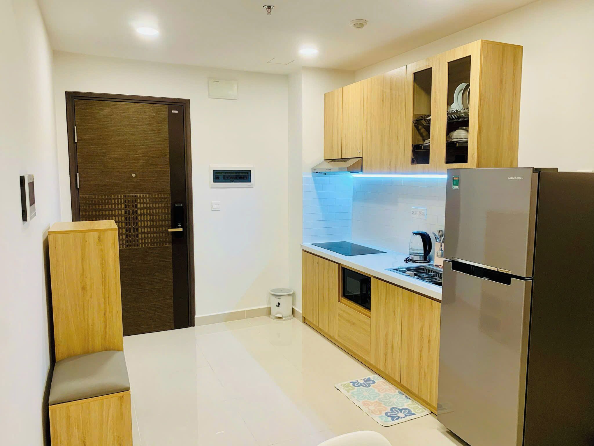 Una cucina compatta con mobili in legno, un frigorifero in acciaio inox e un forno integrato.