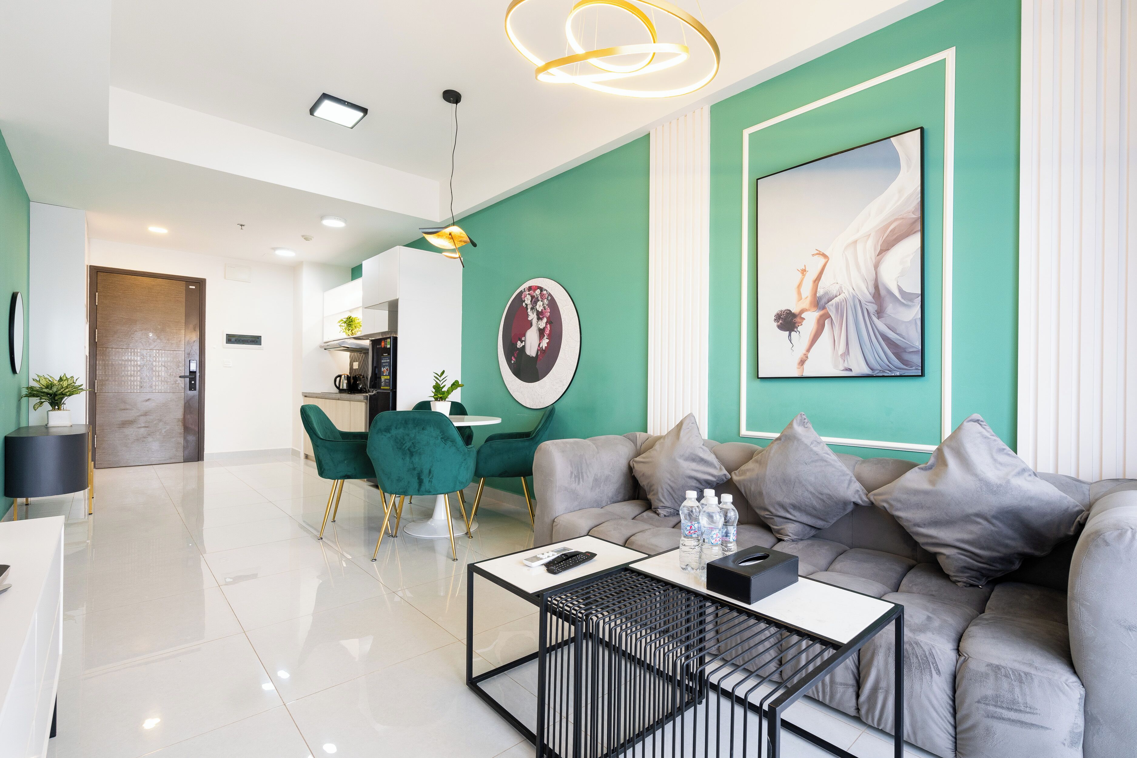 Ein modernes Wohnzimmer mit einem grauen Sofa, Türkiswänden und einem Essbereich mit einem grünen Sessel.