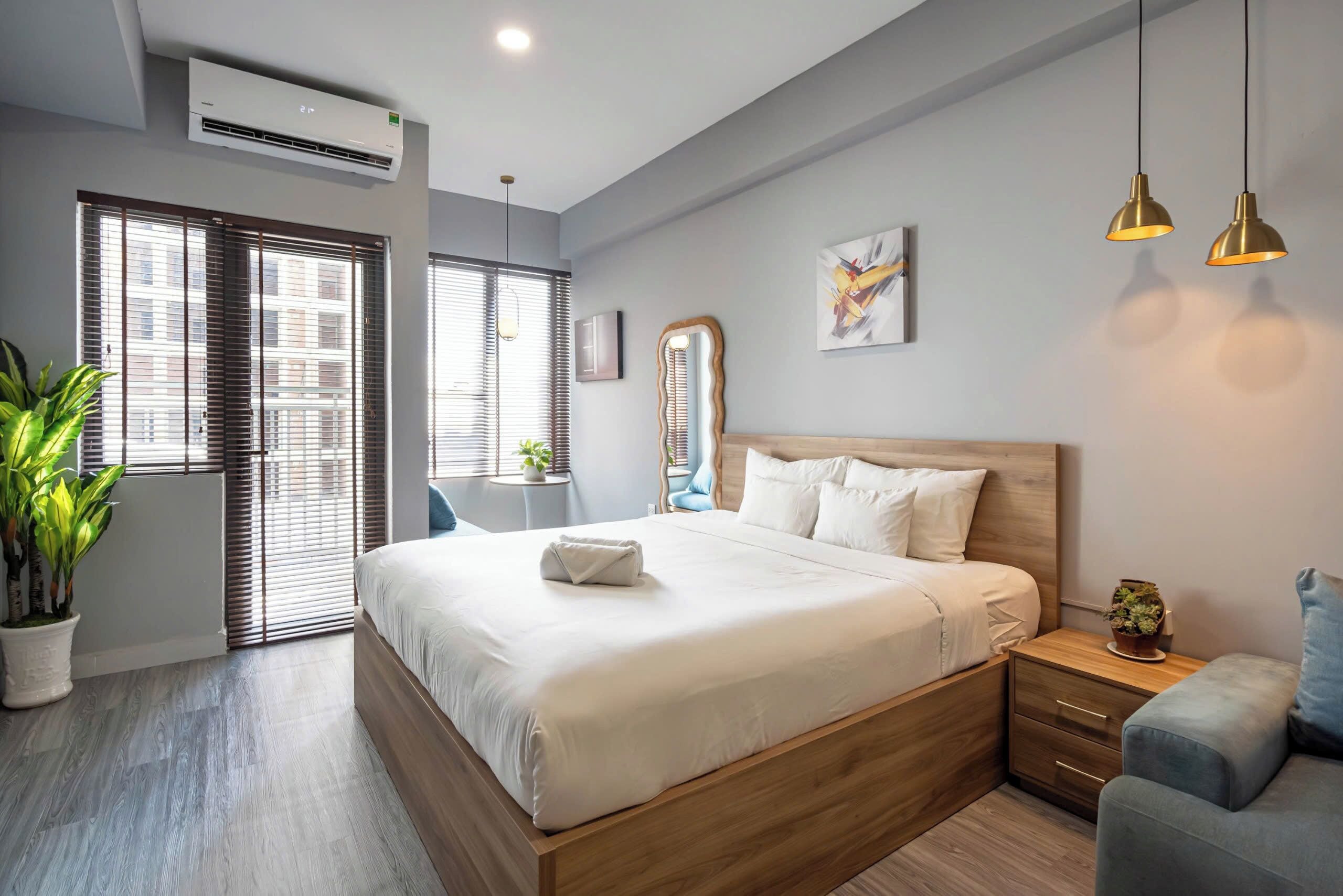 A modern bedroom with a large bed, bedside tables, a mirror, and a potted plant.