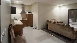 A modern, well-lit room with a kitchen area, a sofa, and a TV. - Wow Grand Serviced Apartments (Jeddah)
