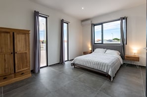 A bedroom with a large bed, wooden wardrobe, and a window with curtains. - Brand New Immaculate 3-bed Villa in Grote Berg (Grote Berg)