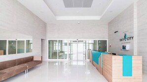 A modern lobby with a reception desk, seating area, and large glass doors leading outside. - MERDZ Spa & Fitness Sky Resident  (Skopje)