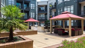 A courtyard with outdoor seating, a grill, and a palm tree. - 2 Bedroom Hip Apartment, Free Parking & Wifi (Charlotte)
