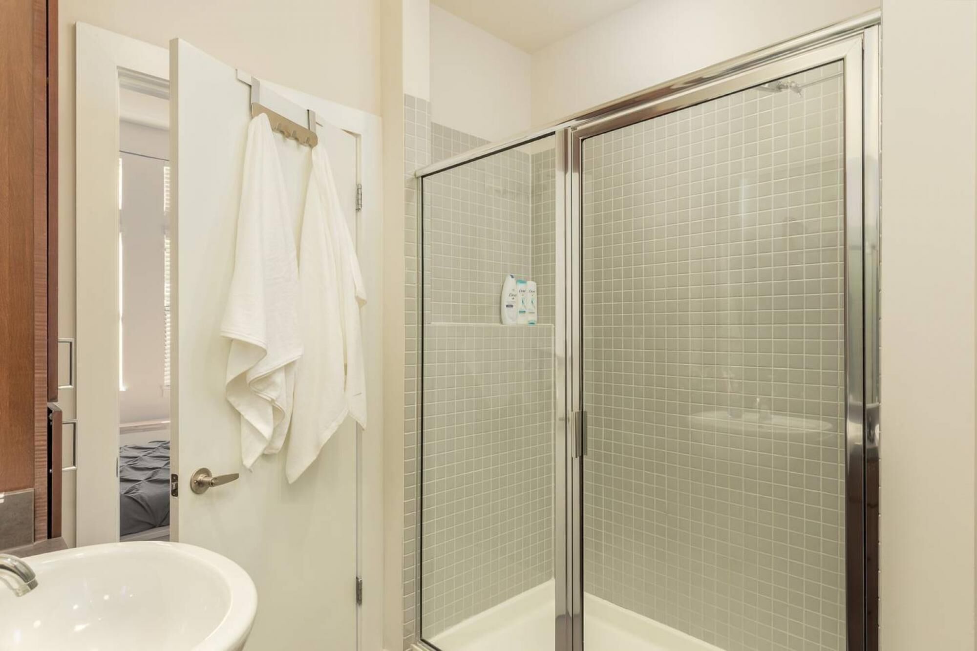 A bathroom with a glass-enclosed shower, a white sink, and a towel rack.