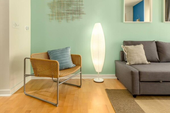 Uma sala de estar moderna com uma poltrona de vime, um abajur e um sofá cinza.