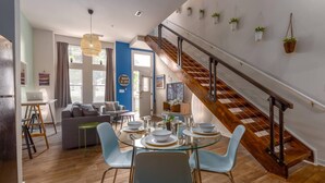 A modern living space with a dining area, a staircase, and a view of the outdoors. - Apartment 10 Min Walk to Epicenter with Wifi (Charlotte)