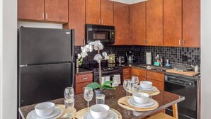 A kitchen with wooden cabinets, a black refrigerator, a microwave, and a dishwasher. - One Bedroom Apartment -10 Min Walk to Epicentre Wifi (Charlotte)