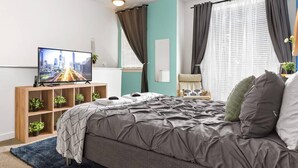 A modern bedroom with a bed, TV, and shelving unit. - One Bedroom Apartment -10 Min Walk to Epicentre Wifi (Charlotte)