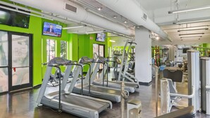 A gym with treadmills, weight machines, and a green wall with a TV. - One Bedroom Apartment -10 Min Walk to Epicentre Wifi (Charlotte)