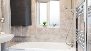 Ein modernes Badezimmer mit Badewanne, einem Fenster mit Pflanze und einer Duschkabine.