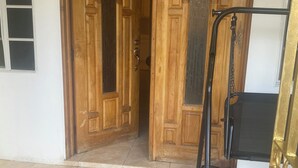 Una puerta de madera con el número '62' encima, que da a un área de entrada con baldosas.