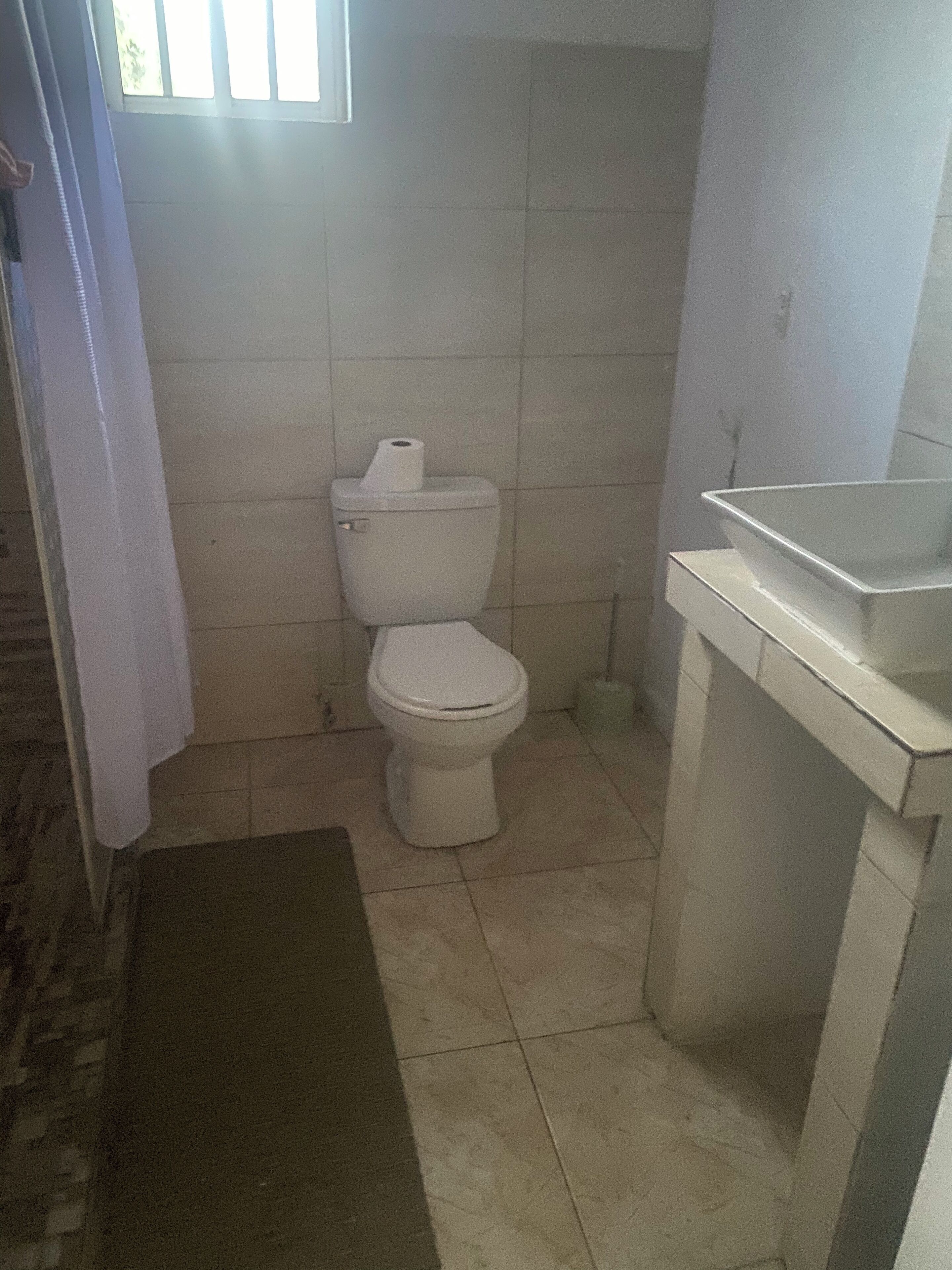Baño pequeño con inodoro, lavamanos y ventana.