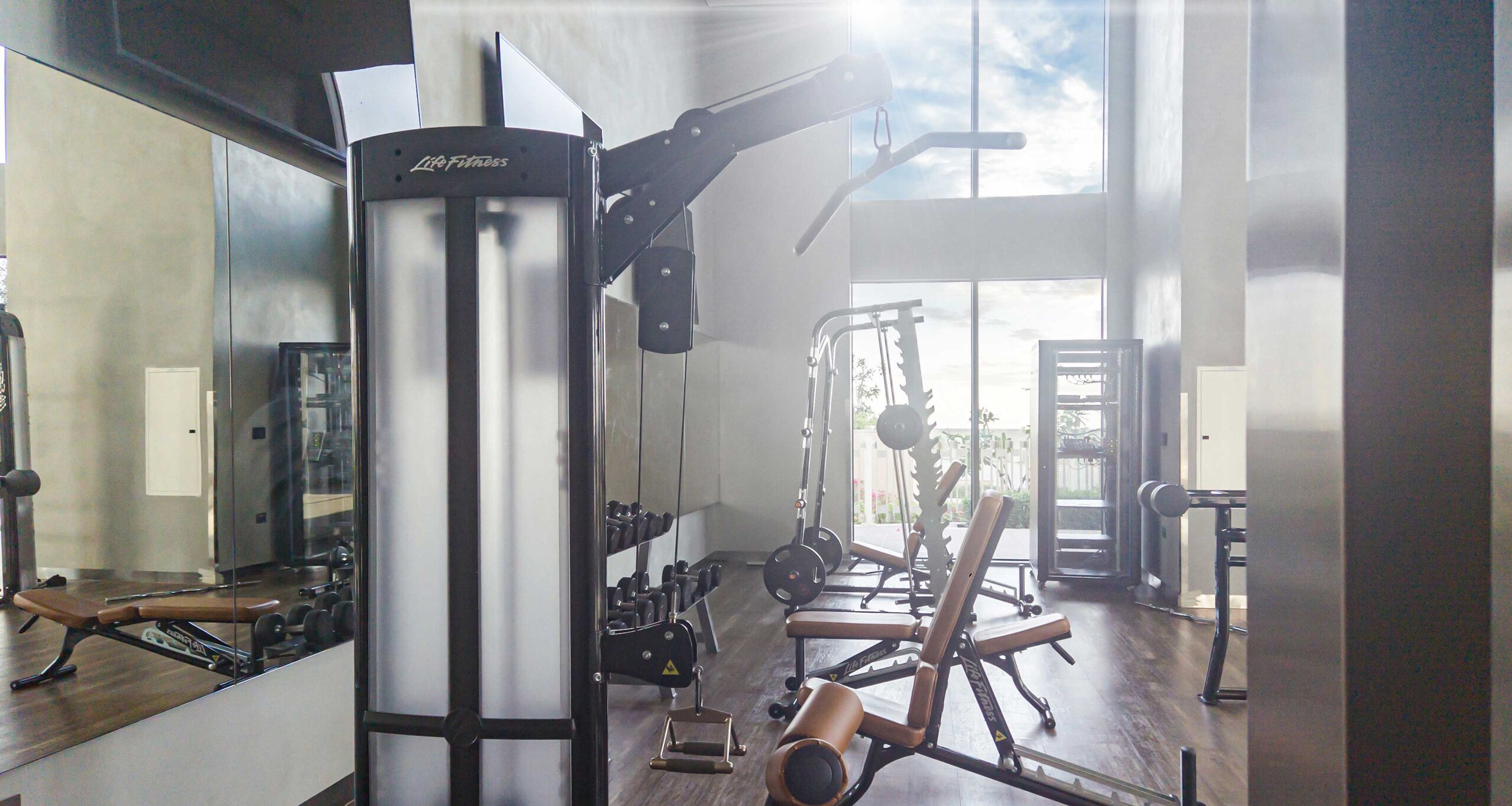 A gym with various exercise equipment, including a bench press, dumbbells, and a squat rack.
