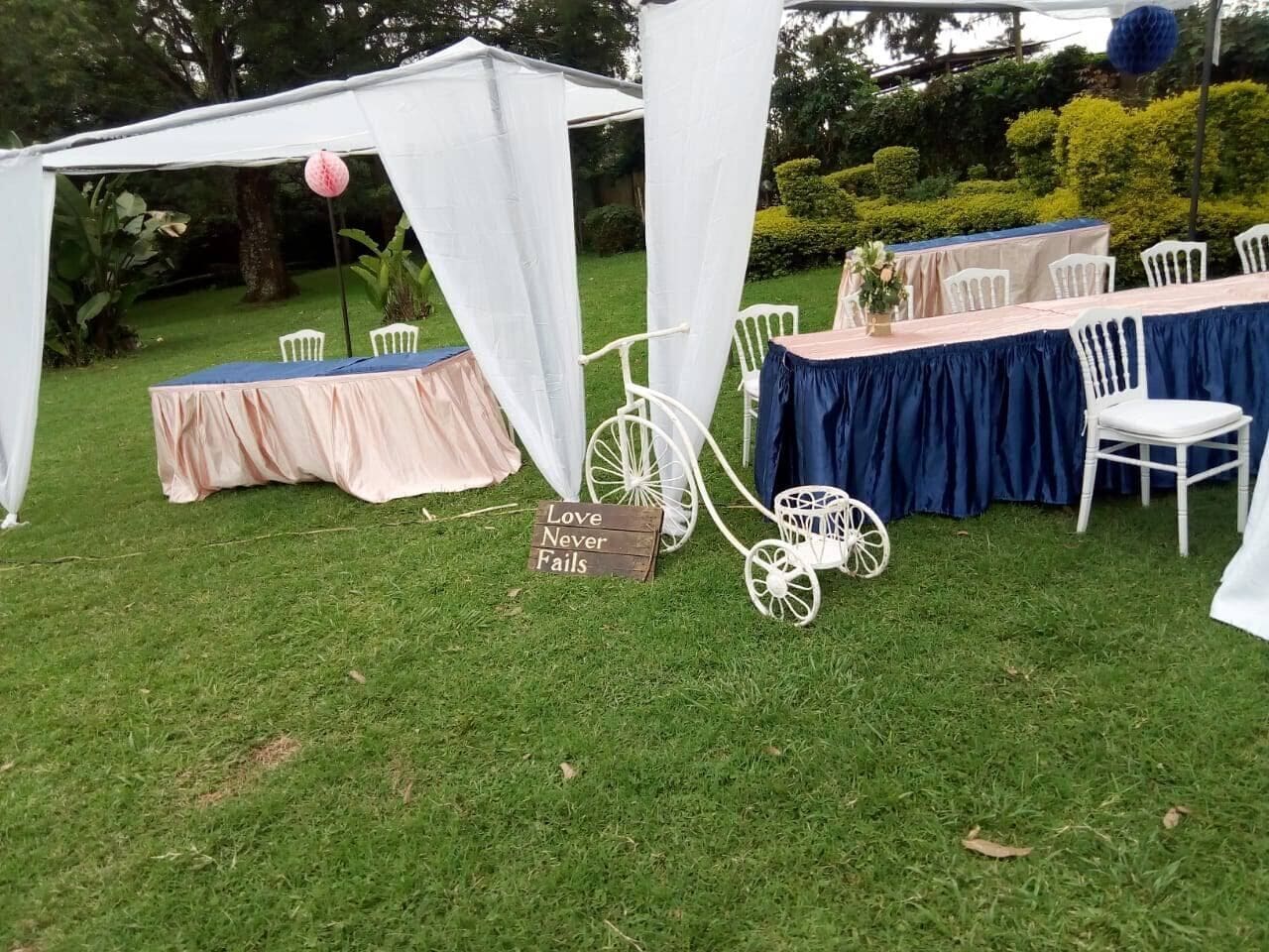 An outdoor event setup with a tent, tables, chairs, and a vintage bicycle.