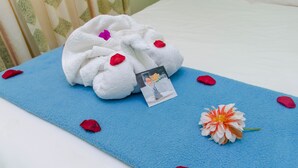 A blue towel with a photo card and a flower on a bed.