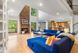 A spacious living area with a blue sofa, a fireplace, and a kitchen in the background.