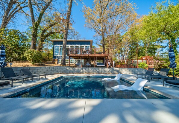 A modern house with a swimming pool, lounge chairs, and a deck.