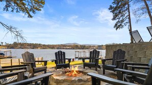 A lakeside seating area with Adirondack chairs and a stone fire pit. - Lakefront Escape | Private Dock | Sleeps 24 (Hot Springs)