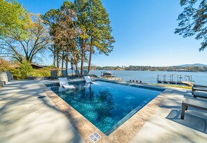A swimming pool with lounge chairs, a dock, and a view of the water. - Modern Lakefront Escape | Private Dock | Hot Tub (Hot Springs)