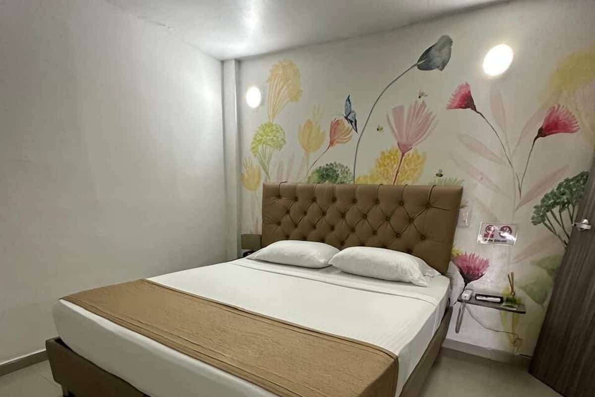 Un dormitorio con cama, mesita de noche y un papel tapiz con motivos florales.