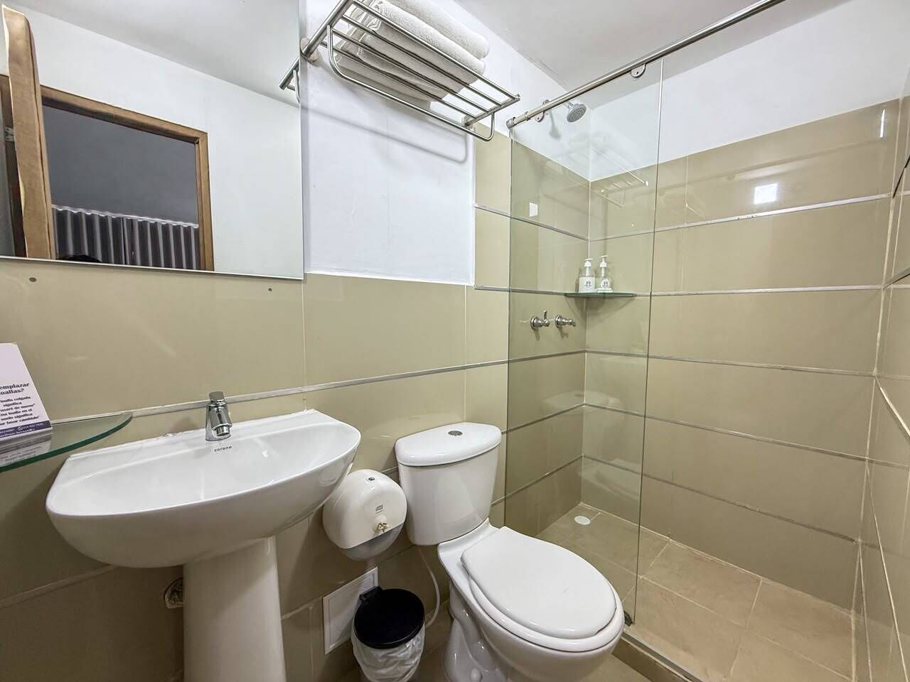 A bathroom with a glass shower enclosure, a sink, and a toilet.