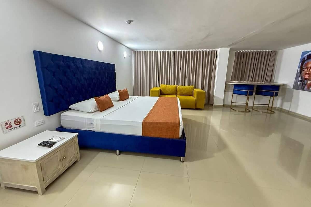 Una habitación de hotel moderna con una cama grande, un escritorio pequeño, un sofá amarillo y una silla azul.