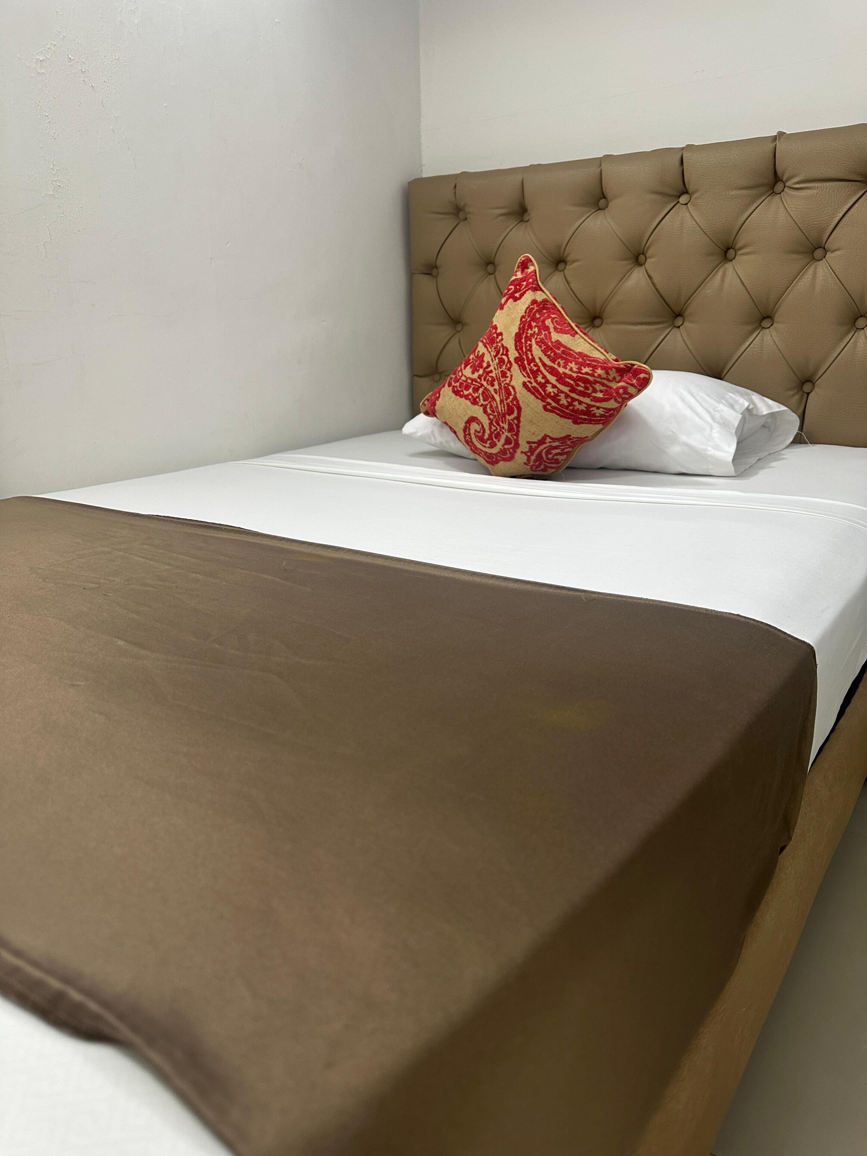 A neatly made bed with a brown bedspread and a single decorative pillow.