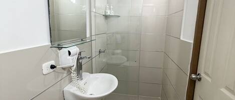 A bathroom with a glass shower enclosure, a white sink, and a towel rack.
